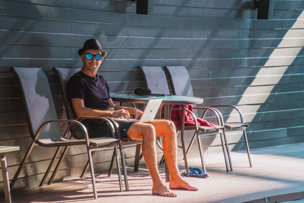 A man working remotely, beside a pool