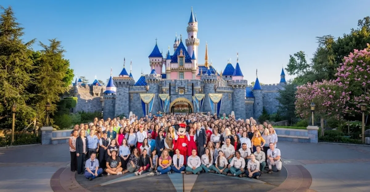 Disney Employee Experience showcased through Disney cast members gathered in front of the iconic Disney castle during a team celebration.