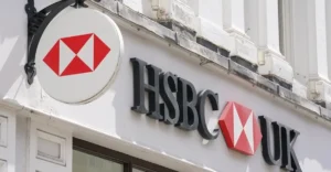 HSBC job cuts in UK wealth: financial adviser meeting a client beside an AI dashboard on a screen