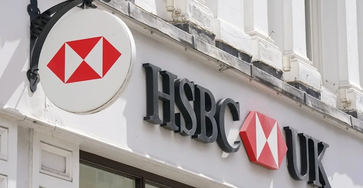 HSBC job cuts in UK wealth: financial adviser meeting a client beside an AI dashboard on a screen